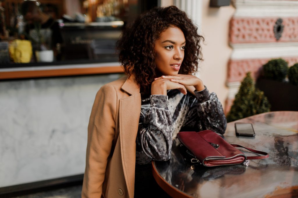 outdoor portrait beautiful smiling black woman with stylish afro hairs sitting cafe paris